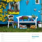 November 2027, 45. Woche. Herbstlich dekorierte Gartenhütte mit Heidekraut, Kürbissen, blauer Holzwand und weißen Möbeln.