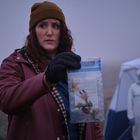 Eine Person hält eine Beweistasche mit vertrockneter Blume, daneben steht jemand in einem Schutzanzug.