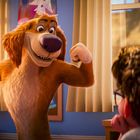 Ein fröhlicher, aufrecht stehender Hund zeigt seine Muskeln in einem Kinderzimmer, vor einem Jungen am Schreibtisch.