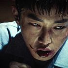 Eine Person mit blutigem Mund und ernstem Blick, die intensiven Emotionen ausdrückt.