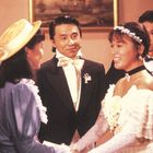 Ein Hochzeitspaar, lächelnd, schüttelt die Hände einer Frau in einem eleganten Setting mit Anzug und Bräutigam in Schleife.