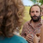 Keine Texte sichtbar. Drei Personen, entspannt im Freien. Ein Mann mit Bart in einem hemd mit Ananasmuster, zwei Frauen lachend.