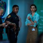 WHEN ‘I’ REPLACED BY ‘WE’ ... ‘ILLNESS’ BECOMES WELLNESS. Zwei Polizisten und eine Frau stehen nebeneinander.