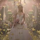 Keine Texte sichtbar. Eine Frau in einem weißen Hochzeitskleid steht inmitten von fliegenden gelben Schmetterlingen.