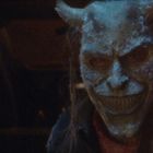 Eine düstere, teuflische Maske mit Hörnern und einem breiten Grinsen, die bedrohlich aus der Dunkelheit schaut.