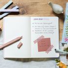 Notizbuch mit Texten: "Ziele 2026", "Ich bin ein Geldmagnet!", "Ich höre auf meinen Körper", "ICH BIN WICHTIG". Pastellfarbenes Ambiente.
