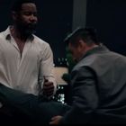 Eine intensiver Kampfszene zwischen drei Männern in einem dunklen, urbanen Raum, einer trägt ein weißes Hemd.