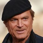 Ich weiß nicht, wer das ist. Ein lächelnder Mann mit schwarzer Mütze und Lederjacke, unscharfer Hintergrund.