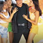 Es gibt keinen sichtbaren Text oder Logos. Ein Mann in Schwarz wird fröhlich von drei Frauen umarmt.