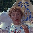 Ein Junge isst Zuckerwatte. Im Hintergrund verzierte historische Kostüme. Fröhliche, lebhafte Szene.