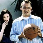Zwei Personen, ein Mann mit einem Basketball, lächelnd, trägt ein gestreiftes Hemd. Eine Frau schaut nachdenklich.