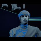 Ein Mann in futuristischer Rüstung mit blauen leuchtenden Akzenten, im Hintergrund geometrische Formen.