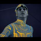 Ich kann keine spezifischen Texte erkennen. Eine Person in einem futuristischen Anzug mit leuchtenden Linien.