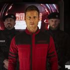 Der Text "RICHARDS" ist auf der Brust einer Person in roter Kleidung. Dahinter stehen zwei uniformierte Männer in Schwarz.