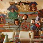 Text "Playa Romántica PIRATE CREW" auf einem Piratenschiff-Dekor. Menschen posieren hinter Piraten-Figuren.
