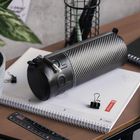 Buchstaben "studio" auf einer schwarzen Röhre, daneben ein weißer Spiralblock und schwarze Büroklammern auf einem Tisch.