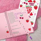 Ein rosa Notizbuch auf pinker Decke, gefüllt mit handgeschriebenen Lieblingssachen wie Bücher und Hobbys, daneben ein Stift.