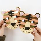 Zwei gebastelte Tiger-Masken mit goldenen Streifen. Hände halten die Masken.