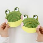 Zwei Hände halten bastelartige Froschgesichter mit grünen und gelben Papierteilen.