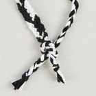 Schwarz-weiße geflochtene Schnur, die in einem Knoten gebunden ist.