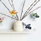 Zweige in weißer Vase, dekoriert mit Filz-Schmetterlingen in Gelb, Rosa, Grün und Blau.