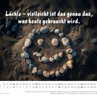 "Lächle – vielleicht ist das genau das, was heute gebraucht wird." Kalender Oktober 2027 zeigt Steine als Smiley im Sand.