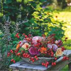 Kalender: September 2027. Ein Blumenarrangement mit Hagebutten auf einem Tisch im Garten.