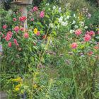 Ein Taubenhaus im Garten von Karl Foerster. Umgeben von farbenfrohen Blumen und Bäumen. Unten Kalender für September.
