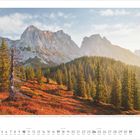Blick vom Lehningspitzl auf die herbstlich gefärbte Landschaft der Ennstaler Alpen. Im Hintergrund hohe Berge. Unten Kalender.
