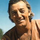 Ich kenne den Mann nicht. Er lächelt, hat braune Haare, trägt ein beiges Hemd, blauer Himmel im Hintergrund.