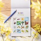 "BINGO im Frühling" steht über einer Karte mit Frühlingsmotiven wie Blumen, Tieren und einem Regenbogen. Ein Bleistift liegt daneben.