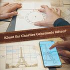"Könnt ihr Charlies Geheimnis lüften?" Zwei Hände arbeiten an Rätseln: eine Rosette, der Eiffelturm auf Papier und Smartphone.