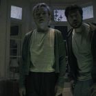 Oben links steht "REC" in weiß mit einem roten Punkt. Zwei Personen schauen in Richtung Kamera. Linien wie bei einer Videokamera.