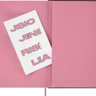 Ein rosa geöffnetes Notizbuch mit einem weißen Blatt. Darauf stehen die Namen JISOO, JENNIE, ROSÉ, LISA in rosa Buchstaben.