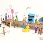 „Have a dinner party!“ Zahlreiche bunte Objekte und Figuren sitzen an einem langen Tisch aus Karton in fröhlicher Szene. 