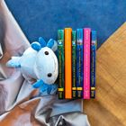 Texte: "The Last Immortals: Dawn of the Axolotl", "Rise of the Rebels", "KitB". Ein blaues Kuscheltier liegt neben Büchern.