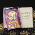 Buchcover: "Which Way to the Future" von Cressida Cowell. Offenes Buch mit Text über fünf Kinder mit magischen Fähigkeiten.