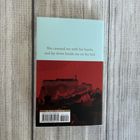 Text: "She caressed me with her hands, and lay down beside me on the bed." Hintergrund: Rotes Gebäude auf dunkelrotem Hintergrund.