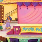 „Masala Magic Dance Recital“ steht auf einem gelben Banner. Eine Familie steht vor einer bunt geschmückten Bühne.