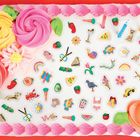 Eine Torte mit großen, bunten Zuckergussrosen und vielen kleinen, dekorativen Objekten wie Früchten, Tieren und Symbolen.