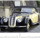Text: "BMW 328", "CASARES EDITION". Ein klassisches Auto in Schwarz und Creme auf einer gepflasterten Straße.