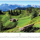 Text: Österreich, Wilder Kaiser, Tirol. Zahlreiche Bäume, Wiesen, Hügel, eine Hütte und ein Pfad unter einem strahlend blauen Himmel.
