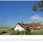 "Ahrenshoop Grenzhaus", Kalender für Mai. Ein Reetdachhaus am Strand in den Dünen, blauer Himmel im Hintergrund.