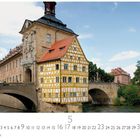 Bamberg, Altes Rathaus. Kalenderseite mit Brücke und Fachwerkgebäude über einem Fluss unter blauem Himmel.