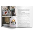 Eine aufgeschlagene Zeitschrift zeigt rechts Text über Rom. Links sind Fotos von Kaffee, Erdbeeren und einer Eingangstür.