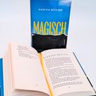 Buchcover mit "Magisch" von Annika Büsing. Offenes Buch zeigt Kapitelüberschrift "Neuntes Kapitel" auf Seite 87.