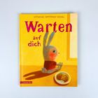„Warten auf dich“. Ein Hase sitzt vor einem Fenster, betrachtet Kekse auf einem Teller.