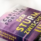 "Der Sturm zwischen uns" von Carley Fortune. Der Einband ist in Violetttönen gehalten.