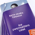 Text: "RUTH-MARIA THOMAS", "DIE ZWEITGRÖSSTE LIEBE". Ein lilafarbenes Buch mit silbernem Leseband.