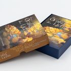 „Das Orakel des Lichts“ steht auf einer bunten Schachtel mit gelben Blumen. Die Verpackung ist elegant gestaltet.